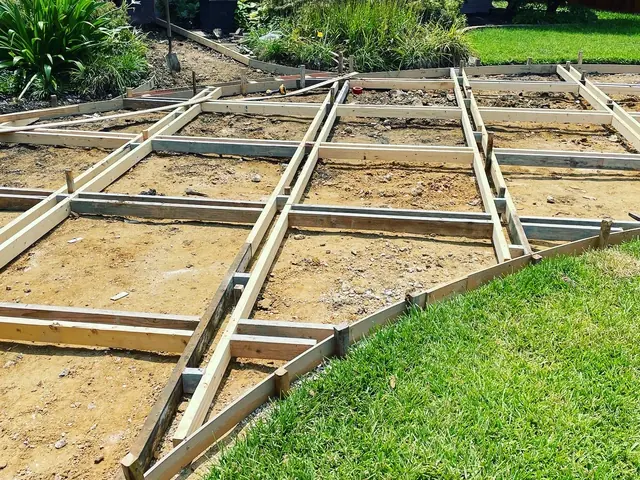 Timber forms set out in a grid over graded sand, with the curved edge of the bay already framed and lawn right up against it