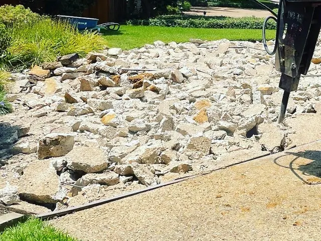 The same job close in: the breaker point down in the broken concrete, with the lawn and planting beyond it untouched