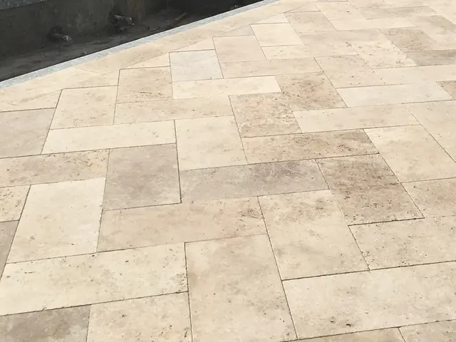 A finished travertine deck close up, laid in a French pattern of four tile sizes with tight joints