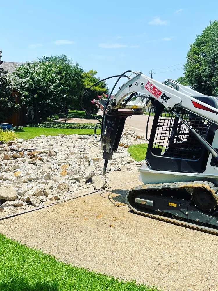 The same trade at the other end: a hydraulic breaker at work in a pile of broken driveway concrete