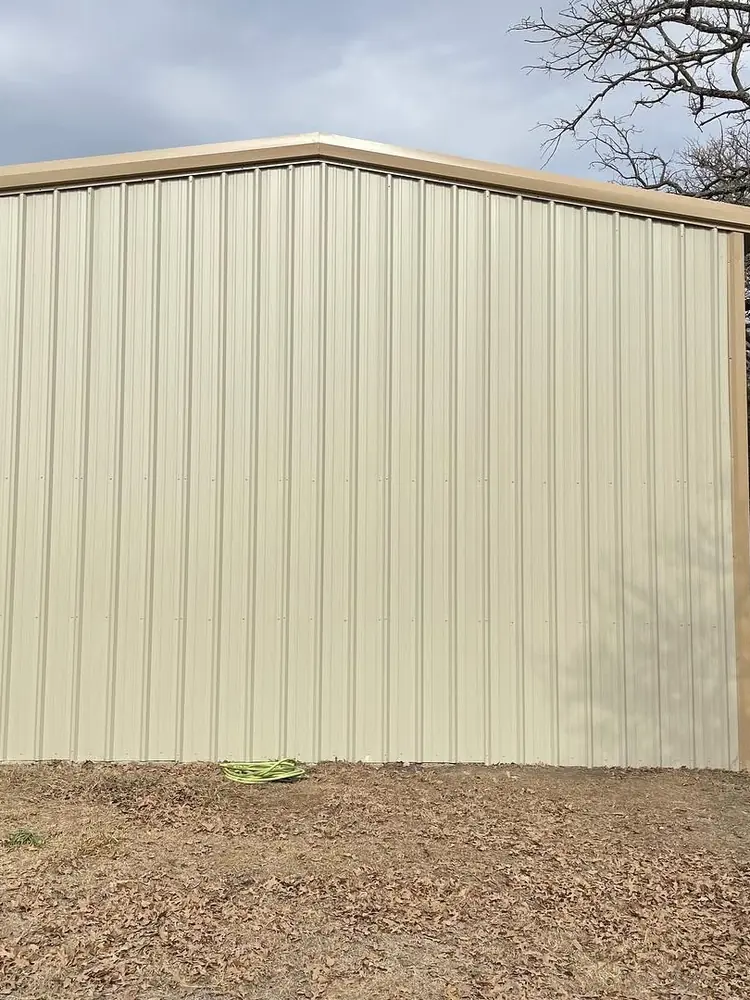 The side of a finished metal building, seen upright, with the wall sheeting running up to the eave line
